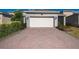 Wide driveway with a two-car garage featuring a brick-paved driveway and manicured landscaping at 11051 Bostwick Aly, Winter Garden, FL 34787