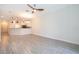 Open-concept living room featuring wood-look flooring, a ceiling fan, and access to the kitchen at 1173 Trappers Trail Loop, Champions Gate, FL 33896
