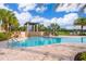 Beautiful community pool with palm trees and pergola for shade on a sunny day at 1173 Trappers Trail Loop, Champions Gate, FL 33896