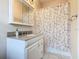 Bathroom with granite countertop, vanity with modern fixtures, decorative mirror, and a shower with patterned curtain at 125 Prima Dr, Poinciana, FL 34759