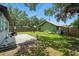 Backyard showcasing lush green grass, mature trees, a concrete patio, a fenced perimeter, and a shed at 1322 New York Ave, St Cloud, FL 34769
