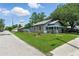 Gray home featuring a fenced yard, blue porch roof, and lush landscaping at 1322 New York Ave, St Cloud, FL 34769