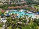 Aerial view of community pool with palm trees, lounge chairs, and Mediterranean-style clubhouse at 1416 Oak Marsh St, Davenport, FL 33837
