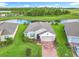 An aerial shot showcases a beautifully landscaped home with stone accents, a brick driveway, and a nearby pond at 159 Olympus Way, Kissimmee, FL 34759