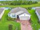 An aerial view of a home with stone accents, shutters, a brick driveway, and well-maintained landscaping by a pond at 159 Olympus Way, Kissimmee, FL 34759
