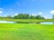 Large green backyard overlooking a pond on a bright sunny day at 159 Olympus Way, Kissimmee, FL 34759