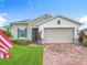 A charming home features stone accents, shutters, a brick driveway, and a beautifully landscaped yard with flag at 159 Olympus Way, Kissimmee, FL 34759