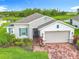 A charming home features stone accents, shutters, a brick driveway, and a beautifully landscaped yard at 159 Olympus Way, Kissimmee, FL 34759