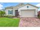 A charming home boasts stone accents, a brick driveway, shutters, and well-maintained landscaping at 159 Olympus Way, Kissimmee, FL 34759