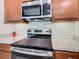 Close-up of the range showing stainless steel appliances, granite countertops, and white tile backsplash at 159 Olympus Way, Kissimmee, FL 34759