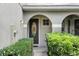 Charming home entry with an arched doorway, decorative glass door, and neatly trimmed green hedges at 196 Canterbury Bell Dr, Oviedo, FL 32765