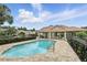 Community pool featuring a pool house with a red tile roof, surrounded by brick pavers and black fencing at 196 Canterbury Bell Dr, Oviedo, FL 32765