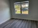 Bright bedroom featuring a large window, white walls, wood-look flooring, and minimalist design at 202 Bromwich Dr, Kissimmee, FL 34758