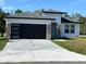 Modern home featuring a black garage door, stone accents, well-manicured lawn, and a concrete driveway at 202 Bromwich Dr, Kissimmee, FL 34758