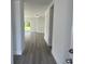 Hallway view into the bright, open-concept living room with wood-look flooring and sliding glass doors at 202 Bromwich Dr, Kissimmee, FL 34758