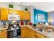 Efficient kitchen with oak cabinets, modern appliances, and a breakfast bar overlooking the living room at 2585 Maneshaw Ln, Kissimmee, FL 34747