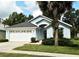 Attractive home showcasing a lovely manicured front lawn, complemented by mature trees and a 2-car garage at 2591 Oneida Loop, Kissimmee, FL 34747