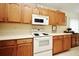 Efficient kitchen featuring wooden cabinets, white appliances, and ample counter space at 2591 Oneida Loop, Kissimmee, FL 34747