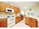 Functional kitchen featuring white appliances, wooden cabinets, and tile flooring at 2591 Oneida Loop, Kissimmee, FL 34747