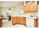 Practical kitchen area with wooden cabinets, white appliances, and views into the dining room at 2591 Oneida Loop, Kissimmee, FL 34747