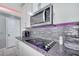Close up on kitchen cooktop with granite counters, gray backsplash, and modern stainless appliances at 2824 Noble Crow Dr, Kissimmee, FL 34744