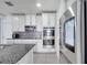 Bright kitchen with stainless steel appliances, gray backsplash, and modern white cabinets and lighting at 2824 Noble Crow Dr, Kissimmee, FL 34744