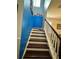 Staircase with stained wood steps and white risers, contrasted by a blue accent wall at 2862 Grasmere View Pkwy, Kissimmee, FL 34746