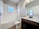 Well-lit bathroom featuring a shower-tub combo, window and dark wood vanity at 301 Terranova Blvd, Winter Haven, FL 33884
