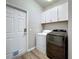 This laundry room has white cabinets and a front loading washer and dryer at 301 Terranova Blvd, Winter Haven, FL 33884