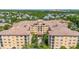 Expansive aerial view of a multi-story apartment complex nestled among lush greenery and a serene water feature at 502 Mirasol Cir # 103, Kissimmee, FL 34747