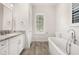 Bathroom vanity with light marble countertops, white cabinets, soaking tub, and a plantation-shutter window at 502 Mirasol Cir # 103, Kissimmee, FL 34747