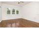 Empty bedroom with hardwood floors, three windows with white shutters, and a ceiling fan at 502 Mirasol Cir # 103, Kissimmee, FL 34747
