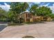 Beautiful tan two-story home with trees shading the brick walkway and beautiful landscaping around the building at 502 Mirasol Cir # 103, Kissimmee, FL 34747