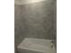 Bathroom with tub and shower featuring gray tiled walls and chrome fixtures at 5793 Gingham Dr, Kissimmee, FL 34758