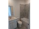 Neutral bathroom featuring tub with gray tiled walls, sink with white cabinets, toilet, and gray floors at 5793 Gingham Dr, Kissimmee, FL 34758