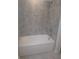 Clean and well-maintained bathroom with gray tile, a white bathtub, and modern fixtures at 5793 Gingham Dr, Kissimmee, FL 34758