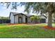 Well-maintained single-story home with grey walls, black trim, mature landscaping, and two-car garage at 6528 Shepherd Oaks Pass, Lakeland, FL 33811