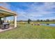 Inviting covered patio featuring a grill and peaceful views of a pond and green space at 8990 Ace Loop, Champions Gate, FL 33896