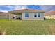 Well-manicured backyard with green grass, outdoor furniture on a patio, and the home's exterior at 8990 Ace Loop, Champions Gate, FL 33896