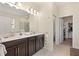 Bathroom featuring double vanity sinks, a large mirror, and entryways to a toilet and walk-in closet at 8990 Ace Loop, Champions Gate, FL 33896