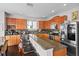 Well-lit kitchen featuring wooden cabinets, stainless steel appliances, and granite countertops with breakfast bar at 11603 Malverns Loop, Orlando, FL 32832