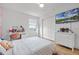 Bright bedroom featuring a large window, a white dresser, closet, and a flat screen television at 1538 Mermaid Way, Haines City, FL 33844