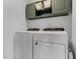 Laundry room features white washer and dryer, olive green cabinets, and plenty of storage space at 1538 Mermaid Way, Haines City, FL 33844