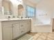 Updated bathroom with dual sinks, modern fixtures, tub, and tile floors at 162 Seneca Point Trl, Kissimmee, FL 34746