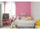 Charming bedroom with pink walls, a white iron bed frame, and natural light from a window at 2547 Raccoon Run Ln, Orlando, FL 32837