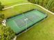 Aerial view of a well-maintained tennis court surrounded by lush greenery and walking paths at 2547 Raccoon Run Ln, Orlando, FL 32837