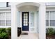 Close-up of the entrance with a dark-blue front door and charming front-porch with plants at 2550 Renshaw St, Kissimmee, FL 34747