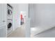 Upstairs hallway with a stacked washer/dryer and view into a bedroom with red curtains at 2550 Renshaw St, Kissimmee, FL 34747