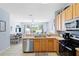 Open kitchen with modern appliances, wood cabinets, and view of dining area and backyard at 2550 Renshaw St, Kissimmee, FL 34747