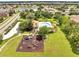 Community aerial view showcasing pool, clubhouse, and playground amidst green spaces and manicured landscaping at 2810 Maguire Dr, Kissimmee, FL 34741